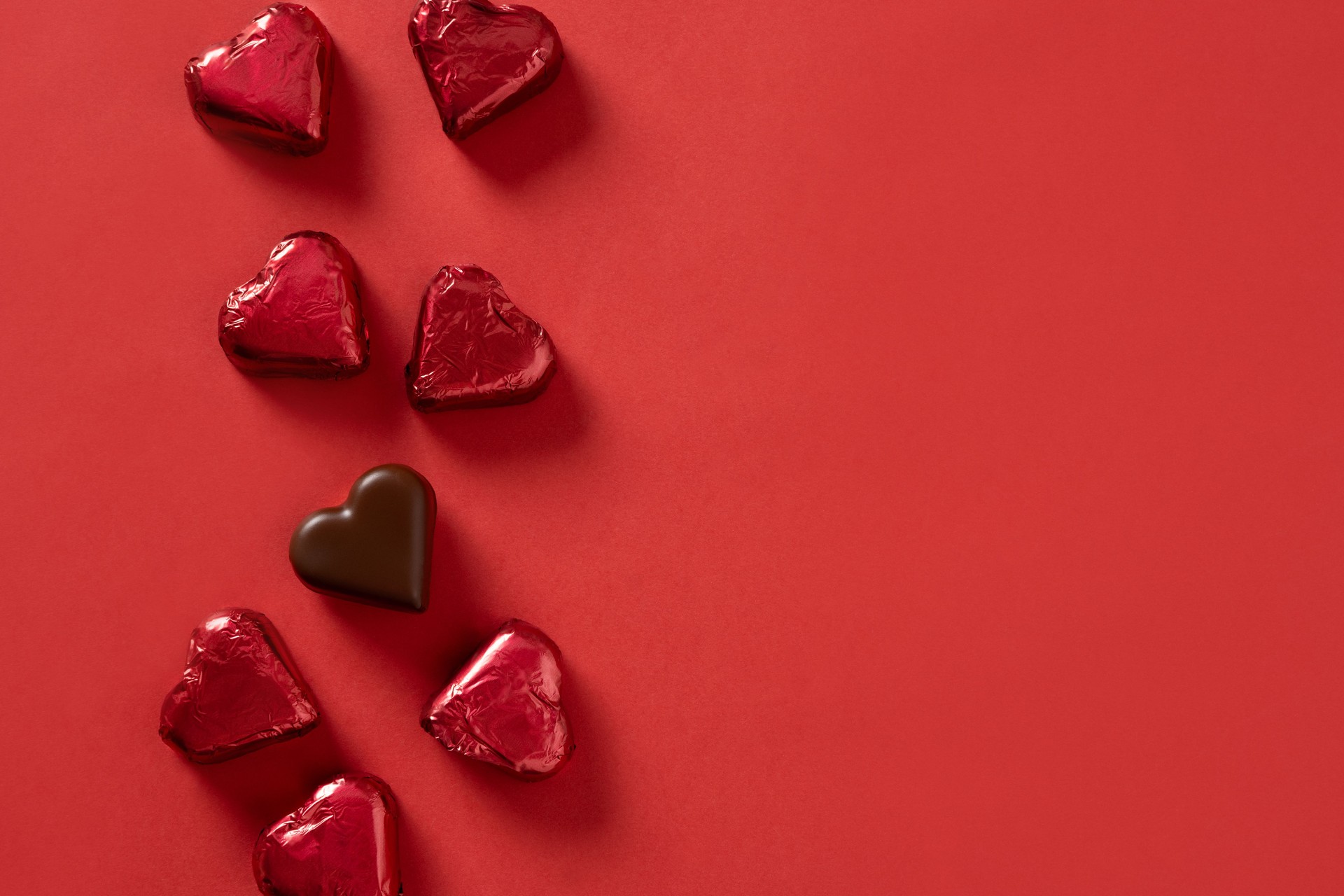 Valentine's day romantic chocolate sweets as heart in red foil as frame.